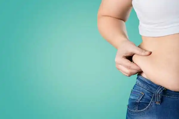 Image of woman pinching her love handles to show weight gain Greenford